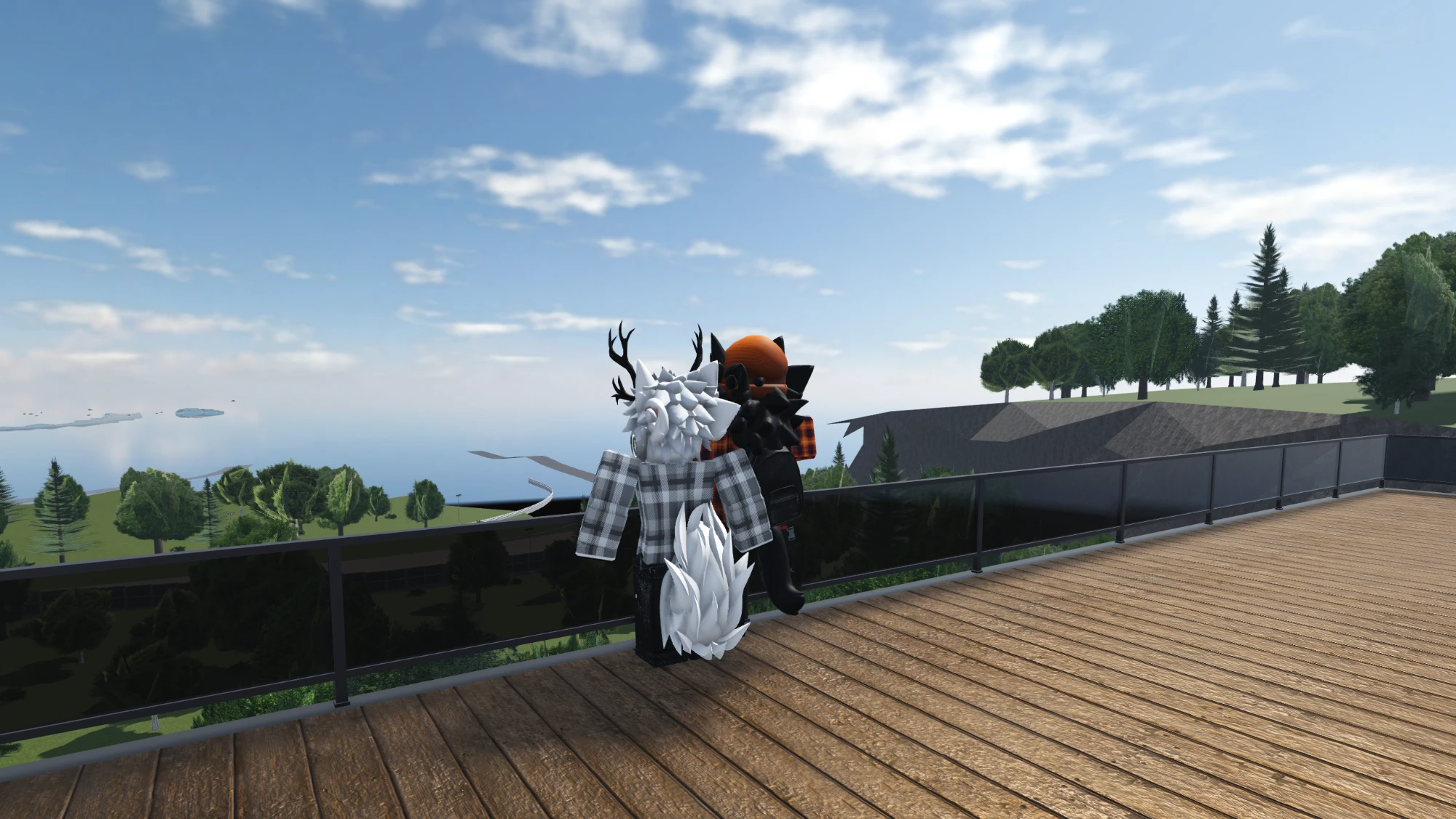 In-game screenshot of Kiro and Kiro's boyfriend as avatars, standing together on a wooden deck looking out over trees and a lake under a bright blue sky.